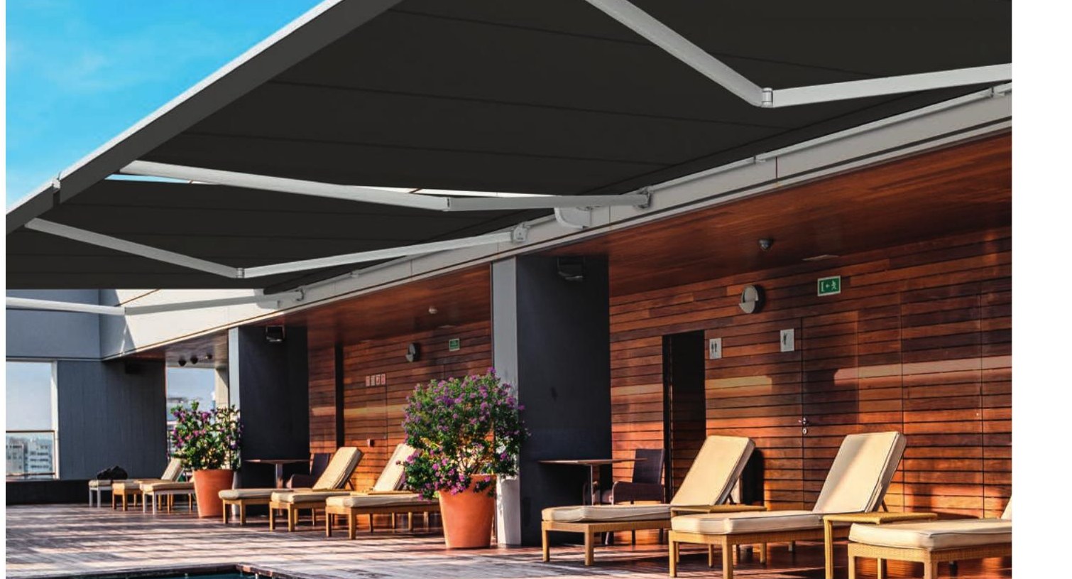 Wide-span Siena Extreme folding arm awning over a poolside lounge